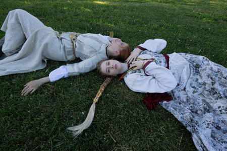 Young women in folk costume in a meadow, in a village among wooden architecture, Slavic or Nordic styleの写真素材