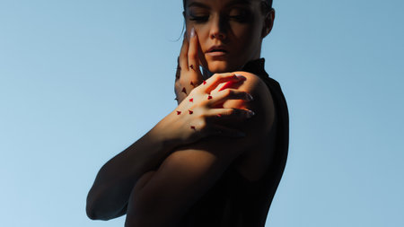 Self-criticism and self-strictness, a concept. A fashion portrait in a melancholic style, a woman with rose thorns on her arm, restrains herselfの写真素材