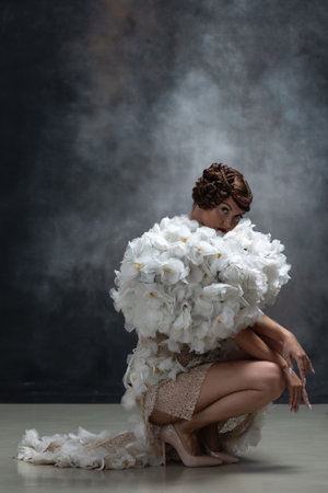 Gorgeous young woman in an extravagant dress with sleeves made of flowers, studio fashion photoの写真素材
