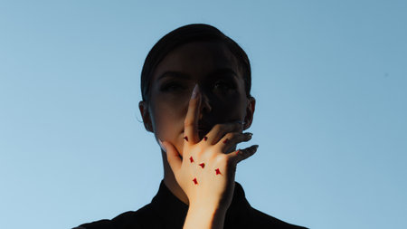 Self-criticism and self-strictness, a concept. A fashion portrait in a melancholic style, a woman with rose thorns on her arm, restrains herselfの写真素材