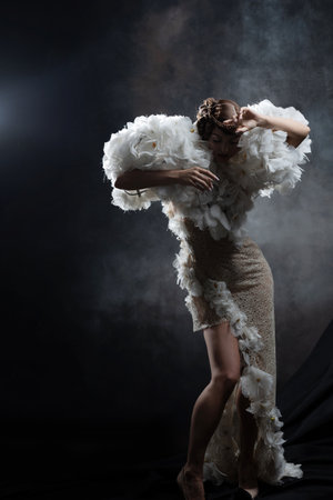 An elegant model with a braid hairstyle in an extravagant dress with sleeves made of flowers, studio fashion photoの写真素材