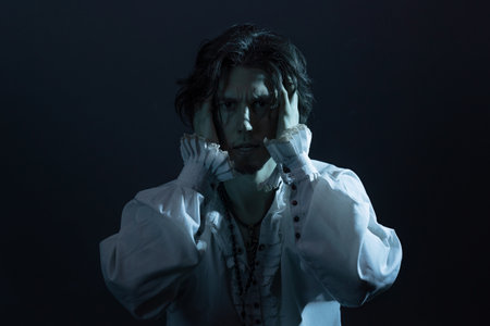 The tragic hero in a white vintage blouse experiences confusion and horror, a portrait in the moonlightの写真素材