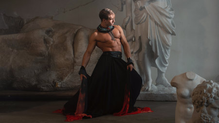 A muscular charismatic man in a silk cape among sculpturesの写真素材