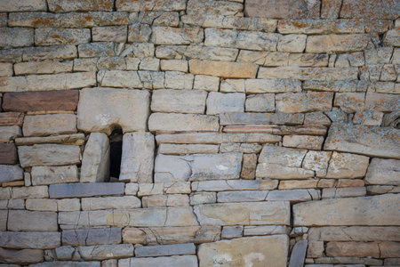 Ancient stonework with a small window in the wall. a wall made of stone slabs or ancient bricks.の写真素材