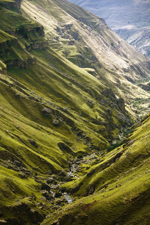 An epic view of a huge mountain rift, the terrain is covered with greenery, the canyon is visible far into the distance.の写真素材