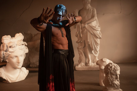 A muscular charismatic bodybuilder in a silk cape among sculpturesの写真素材