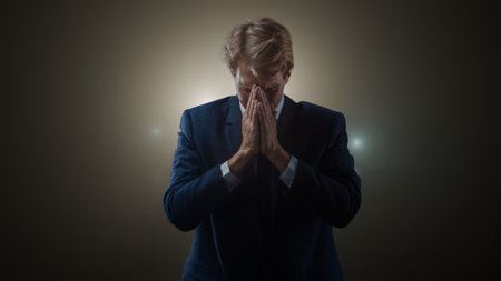 A young man in a business suit is stressed and covers his face with his hands, burnout and problems at work and in life, concept portrait, cinematic volumetric lightingの写真素材