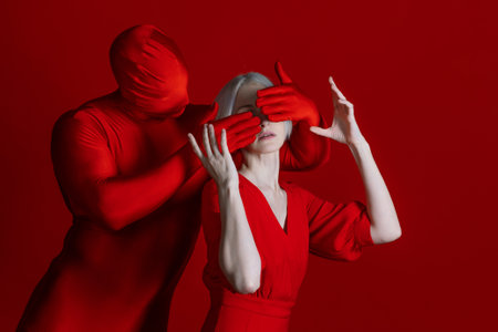 External and internal pressures depicted through artistic composition. A figure in red with hands...