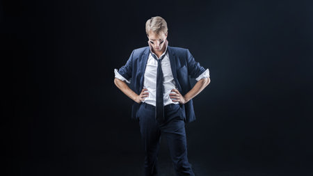 A businessman in a business suit and tie is posing against a dark background. Strength and decisive actionの写真素材