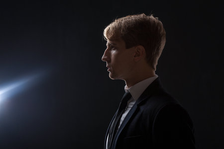 A young businessman in profile. A thoughtful man in a business suit looks into the distance towards a ray of light, venture capital investments and promising markets, conceptの写真素材