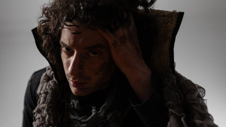 bandit or hero, dramatic character in the style of Shakespeare in a modern way, a young curly-haired man, dirt on his face, complex emotions, worn and dirty clothes, Contrast lighting, super close-upの写真素材