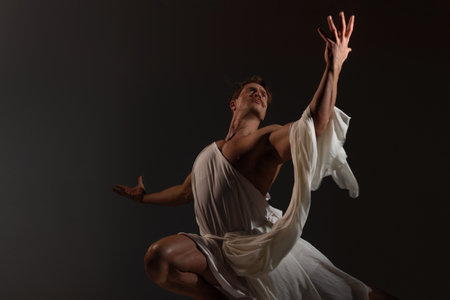 A muscular, athletic figure embodying Zeus, the ancient Greek god of thunder, stands powerfully with a toga draped over his shoulders. Epic pose, tunic flapping in the windの写真素材