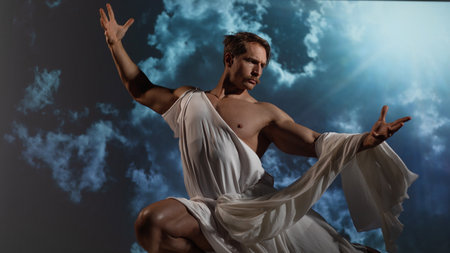 A muscular, athletic figure embodying Zeus, the ancient Greek god of thunder, stands powerfully with a toga draped over his shoulders. dramatic sky on the backgroundの写真素材