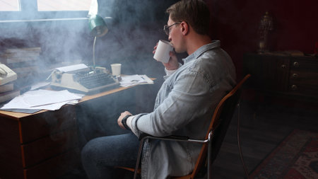 A male writer is working hard on his book, sitting in his vintage-style office, the room is filled with cigarette smoke,cinematic style, soft focusの写真素材