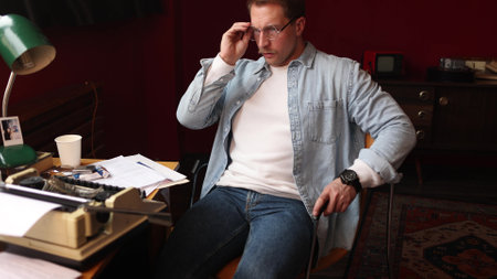 Writer immersed in thought at vintage desk, cinematic soft lighting highlighting typewriter and smoky atmosphere.の写真素材