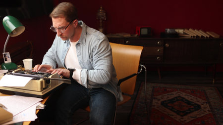 Young male novelist deep in thought at classic typewriter, cinematic portrayal of writing inspiration.の写真素材