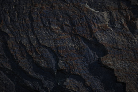 A textured stone background with chiaroscuro lighting, showcasing a brutal, monolithic rock formation. Cracks and fragments highlight its geological power, perfect for design templates or science-themed projects.の写真素材