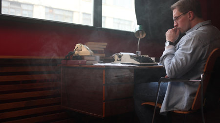 Soft-focused image of a male novelist experiencing creative frustration at his home office desk.の写真素材