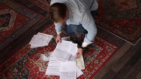Man intensely searches through paper stacks on floor, cinematic portrayal of investigative truth-seeking process.の写真素材