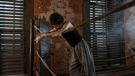 Boxer woman taking break on ropes, intense cinematic training session pause
