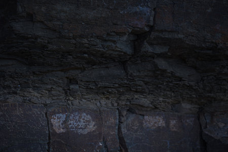 A textured stone background featuring a brutal, monolithic rock formation with cracks and fragments....
