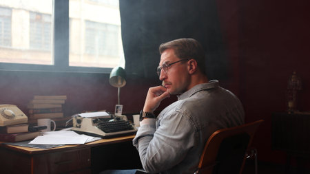 Soft-focused image of a writer struggling with creativity at his cluttered desk, surrounded by books...