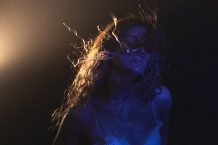 Enigmatic portrait of young beauty, long hair dancing in wind with dramatic lighting and mystical...