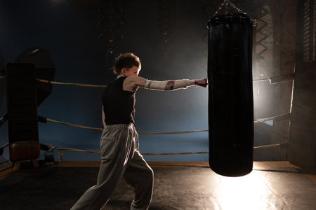 Woman boxer in ring with cinematic lighting, throwing powerful punch during intense trainingの写真素材