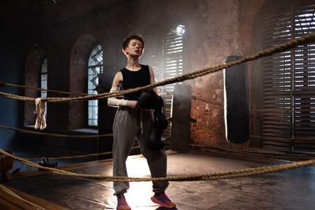 A woman in a boxing ring, wrapping an elastic bandage around her arms, preparing for boxing...