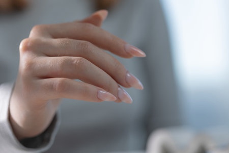 Quiet luxury manicure on elegant hand in salon, light tones with professional tools in viewの写真素材