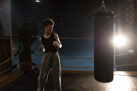Female athlete boxing in dim gym lights, cinematic punch moment with colorful shadowsの写真素材