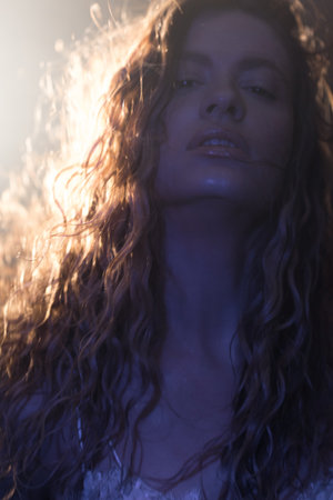Enigmatic portrait of young beauty, long hair dancing in wind with dramatic lighting and mystical atmosphereの写真素材