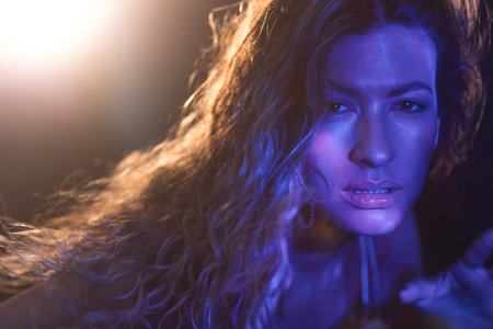 Mystical close-up of woman with windblown hair, cinematic colored lights creating dreamlike...