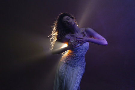 Elegant woman dancing in white gown, mystical atmosphere created by soft backlighting.