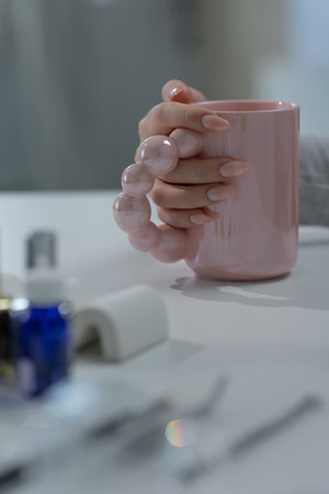 Quiet luxury manicure on elegant hand in salon, light tones with professional tools in viewの写真素材