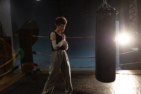 Woman boxer in ring with cinematic lighting, throwing powerful punch during intense training
