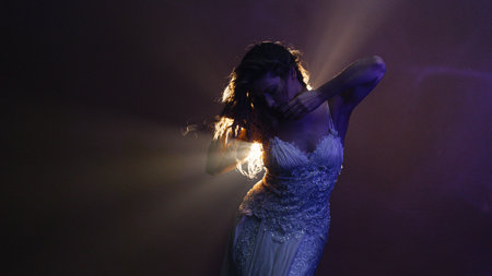 Mystical scene of woman dancing in white dress, glowing backlight creating magical ambianceの写真素材