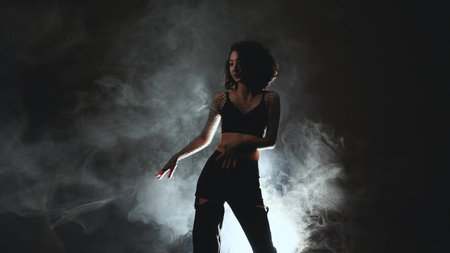 Atmospheric dance performance - female dancer in heels executing fluid movements against moody backdropの写真素材