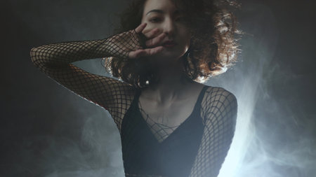 Contemporary dance artistry: female performer in fashionable outfit dancing through atmospheric haze