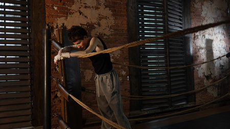 Boxer woman taking break on ropes, intense cinematic training session pause