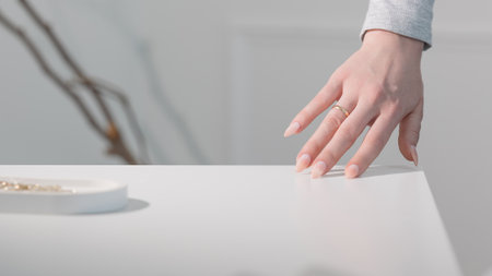 Elegant almond nails with beige gel polish, close-up of glamorous feminine hands in soft light.の写真素材