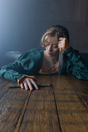 Fair maiden in jewel-toned dress clutches dagger, suggesting royal court betrayal.の写真素材