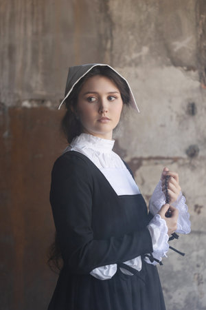 Serene nun in traditional wimple holding rosary within historic monastery walls.