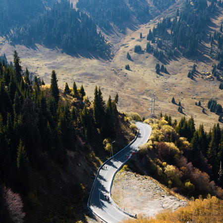 Serpentine road carved into mountainside, weaving through dramatic alpine sceneryの写真素材