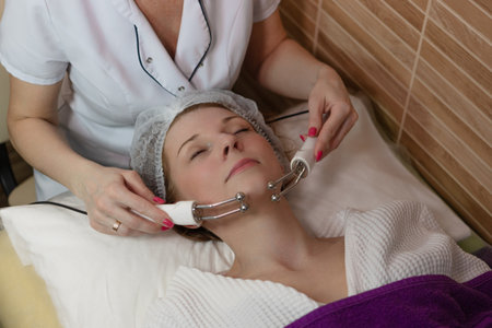 Beauty therapy: woman undergoing microcurrent facial for lifting and lymphatic drainage.の写真素材