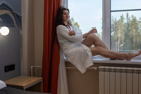 Woman enjoying vacation relaxation in hotel room wearing comfortable white spa robeの写真素材