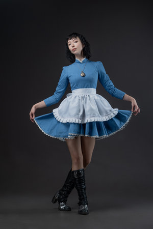 Full-length photo of Gothic Alice in blue Victorian dress with apron on gray.の写真素材