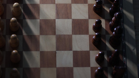 Dynamic video sequence of chess pieces positioned on a slowly rotating chessboard, symbolizing the intellectual confrontation between black and white opposing forces in strategic gameplay. Top view, long shadowsの写真素材