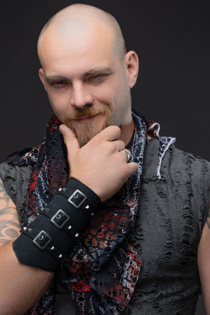 a charismatic bald man in a daring street style, a large picture on a gray background in the studio