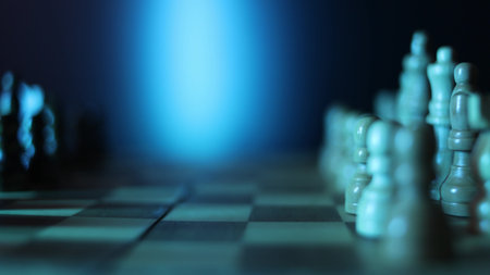 Dynamic video sequence of chess pieces positioned on a slowly rotating chessboard, symbolizing the intellectual confrontation between black and white opposing forces in strategic gameplay. Semi-darkness and blue backlightの写真素材